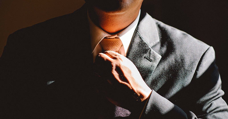 Confident man adjusting tie