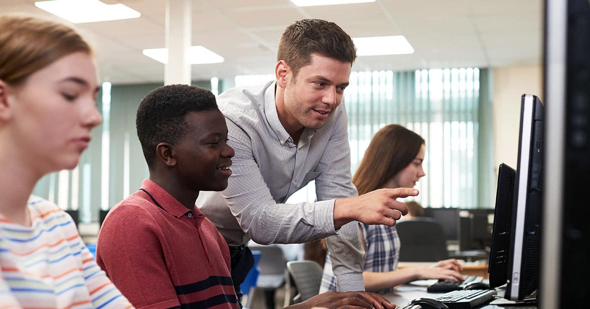 Man helping students in a computer lab