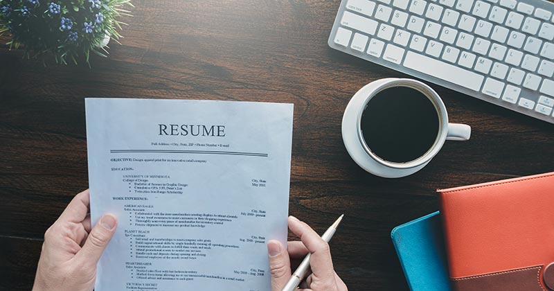 Person at desk reviewing a resume in hand