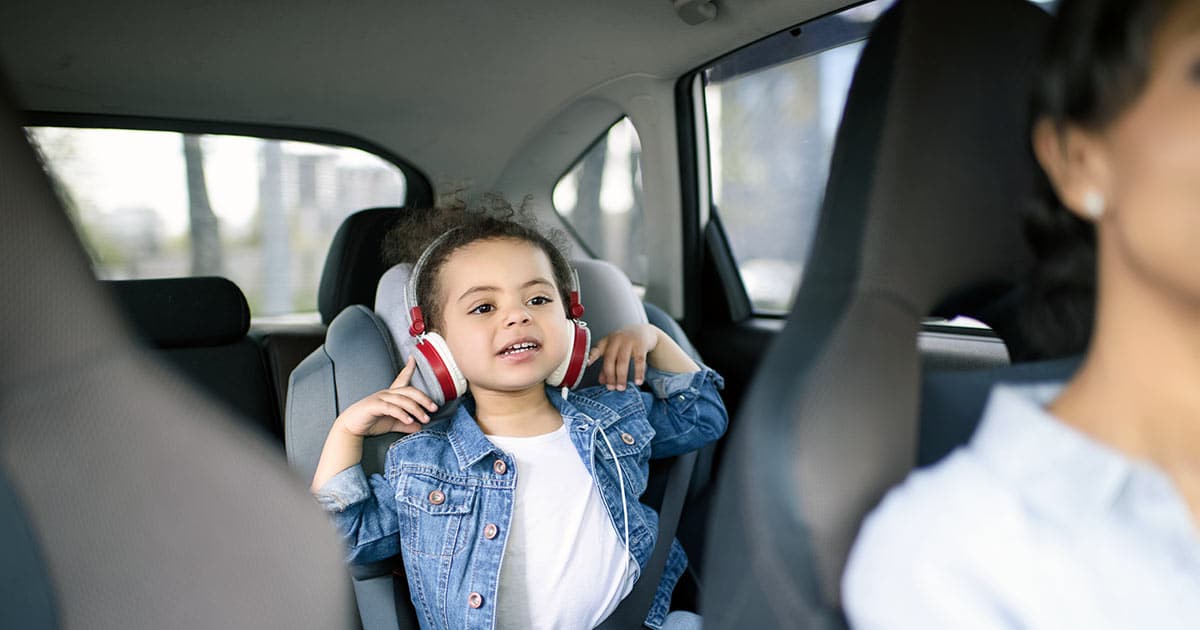 Woman driving a car with her young daughter in the rear