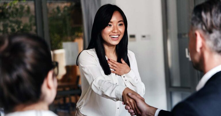 Pleasantly surprised woman congratulated with handshake