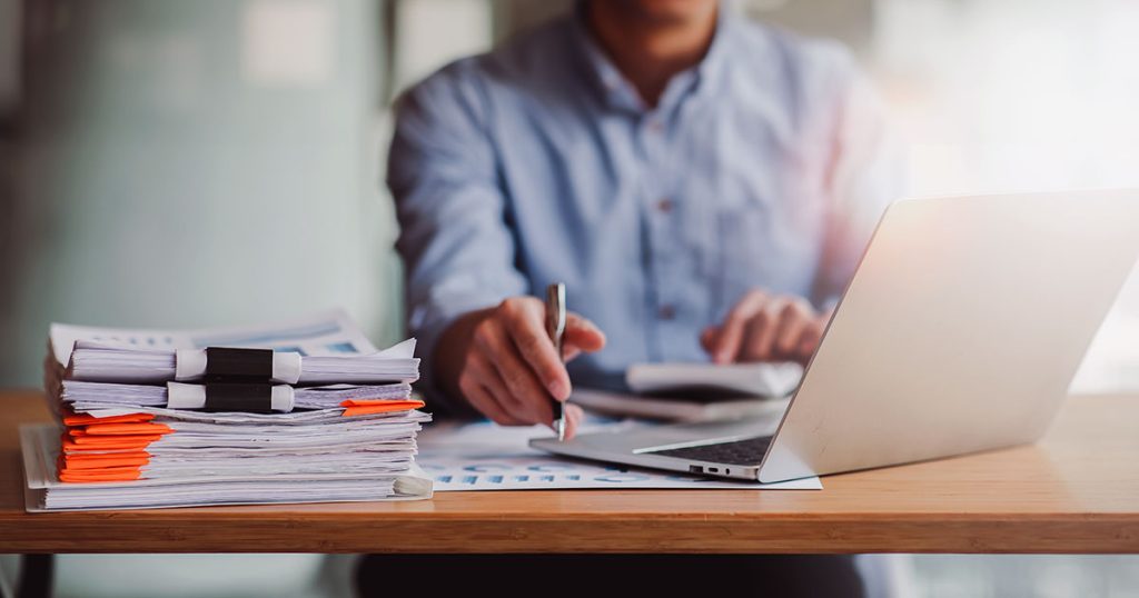 Man working online surrounded by documents