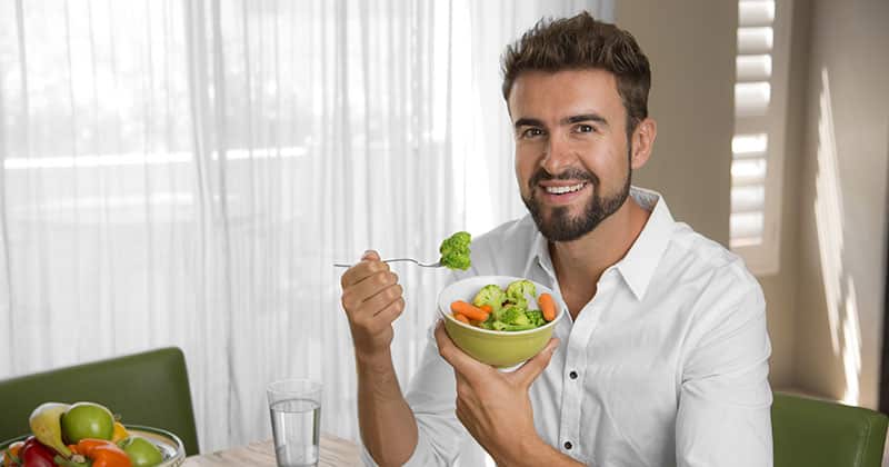 Healthy looking man eating a bowl of unprocessed vegetables