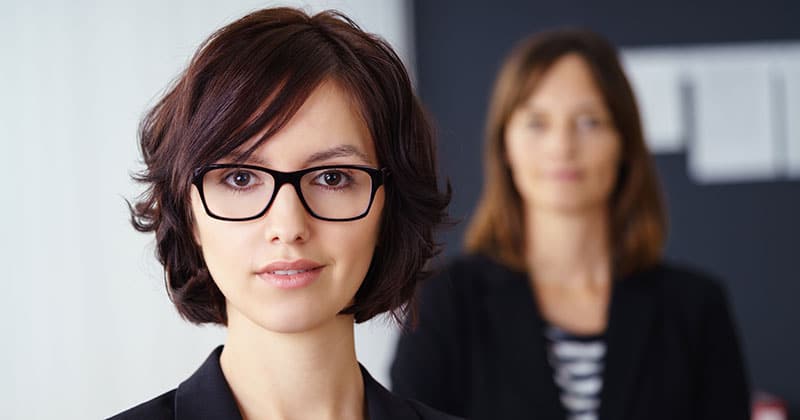 Professional woman with glass with another woman in background