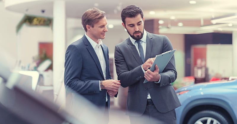 Two male professionals in suits in a car dealership