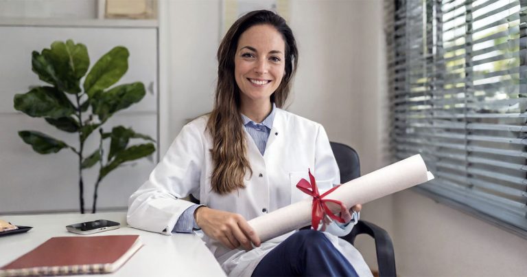 Therapist sitting in office holding a degree